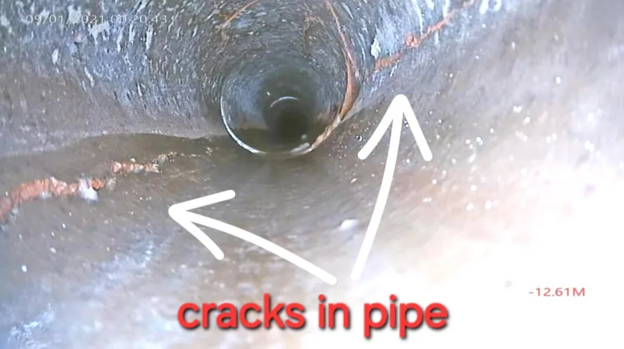 Hairline cracks running along the inner wall of a cast iron sewer pipe
